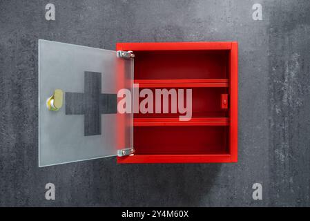Open Red Metal Empty Medicine Cabinet Hanging On A Dark Gray Marble Wall Background. Front View Stock Photo