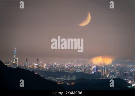 A breathtaking night view of Taipei City skyline with fireworks and a crescent moon on Qixi Festival. The romantic atmosphere is enhanced by the celes Stock Photo