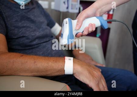 Nurse Scanning QR Code on Patients Paper ID Bracelet in Hospital Surrey England Stock Photo