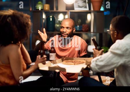 Happy friends, beer and business people talk in office to celebrate Octoberfest party. Alcohol, drink or African team eating pizza or food at social Stock Photo