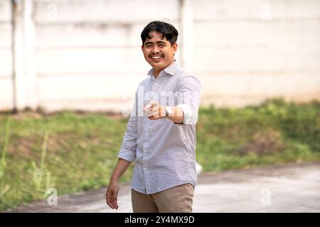 Smiling and pointing to front with finger poses. A guy smiling while pointing at the camera Stock Photo