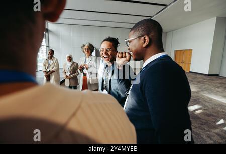 A group of joyful businesspeople laughing and engaging during a meeting in a modern office space. The atmosphere is friendly and collaborative. Stock Photo