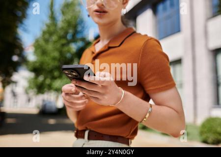 An individual engages with their smartphone while surrounded by greenery and modern architecture. Stock Photo