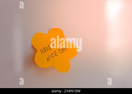 Bright yellow sticky note with a cheerful message on a wall for an uplifting start to the day Stock Photo