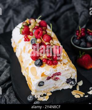 Meringue roll with cream and berries and almonds Stock Photo
