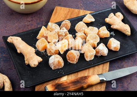 Dried candied ginger pieces and fresh rhizome root, candied ginger dessert. Stock Photo