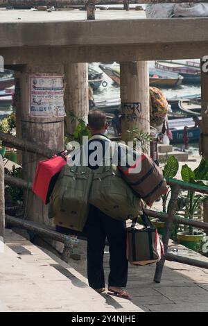 Varanasi, Uttar Pradesh / India - May 9, 2015 : On the Varanasi Ghat, a man is carrying a lot of luggage of pilgrims on his shoulders. Stock Photo