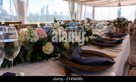 Wide view of outdoor tent with tables decorated with roses for a daytime wedding Stock Photo