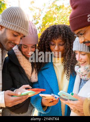 Cheerful group of young friends using cell phones outdoors. Stock Photo