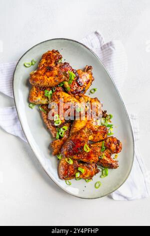 Homemade asia style chicken wings with green onions on serving plate Stock Photo