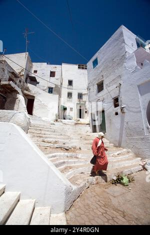 A woman walks down the steps of a charming whitewashed alley in Tetouans historic Medina, showcasing the vibrant local architecture. Stock Photo