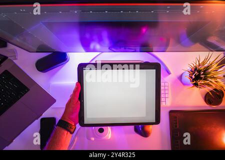 Designer holding graphic tablet project. Home studio equipment laptop monitor glow neon light. Stock Photo