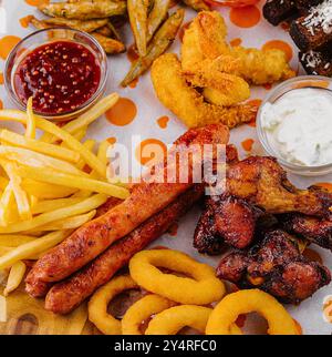 french fries potatoes with onion rings, sausages, croutons and spicy chicken legs Stock Photo