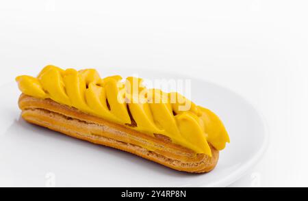 Eclair with Mango Cream on White Plate Stock Photo