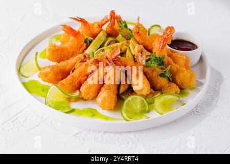 Golden fried shrimp served with slices of fresh lime and dipping sauce, garnished with herbs Stock Photo