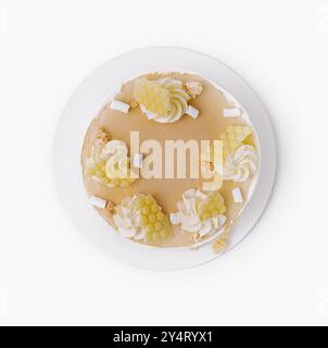 Top view of a lemon cheesecake with white cream toppings and coconut flakes, isolated on white Stock Photo