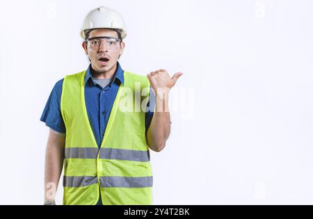 Surprised young engineer pointing side advertising space isolated. Amazed engineer pointing to the side an advertising space Stock Photo