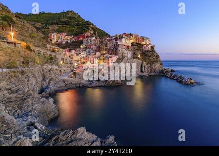 Sunset and night view of Manarola, one of the five Mediterranean villages in Cinque Terre, Italy, famous for its colorful houses and harbor, Europe Stock Photo