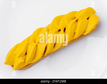 Vibrant mango eclair presented on a pure white circular plate, isolated on white background Stock Photo