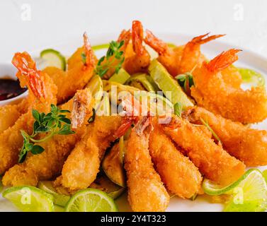 Golden fried shrimp served with slices of fresh lime and dipping sauce, garnished with herbs Stock Photo