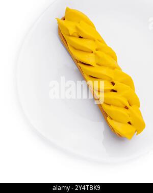 Vibrant mango eclair presented on a pure white circular plate, isolated on white background Stock Photo