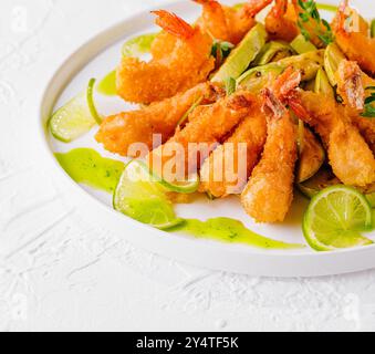 Golden fried shrimp served with slices of fresh lime and dipping sauce, garnished with herbs Stock Photo