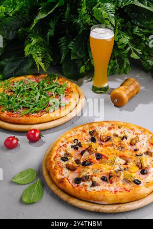Two different pizzas served on wooden boards with a glass of beer, perfect for sharing with friends at a restaurant or at home Stock Photo