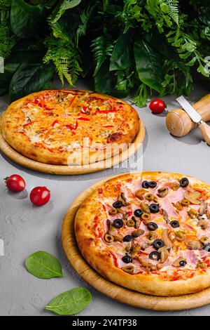 Two different pizzas with melted cheese and different ingredients lying on wooden boards Stock Photo