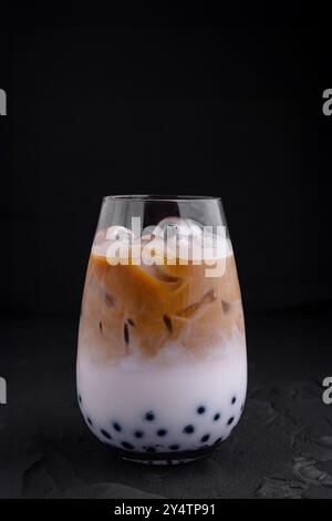 Iced coffee latte with milk and boba tapioca pearls is standing on black background Stock Photo