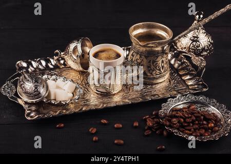 Traditional turkish coffee setup is waiting to be served with its silver pot, cup, sugar bowl and coffee beans on a silver tray Stock Photo