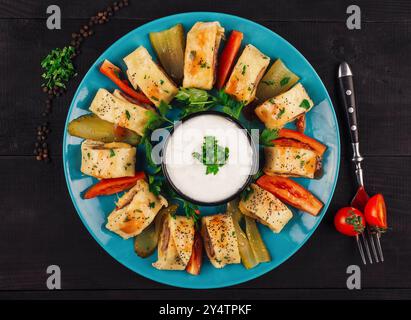 Turkish beyti kebab served on a blue plate with yogurt sauce, tomatoes and pickles Stock Photo