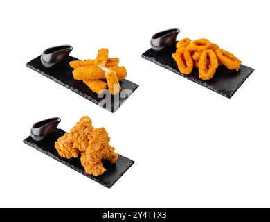 Delicious fried snacks like chicken nuggets, mozzarella sticks, and onion rings are served on a black stone plate Stock Photo