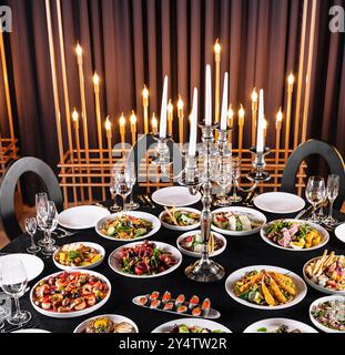 A luxurious dinner setup featuring candles, fine cuisine, and stylish tableware Stock Photo