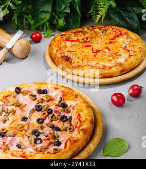 Two different pizzas with melted cheese and different ingredients lying on wooden boards Stock Photo