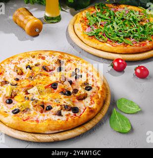Two different pizzas served on wooden boards with a glass of beer, perfect for sharing with friends at a restaurant or at home Stock Photo