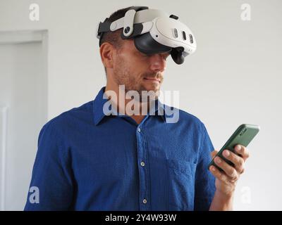 Man in Virtual Reality headset using using phone. Stock Photo