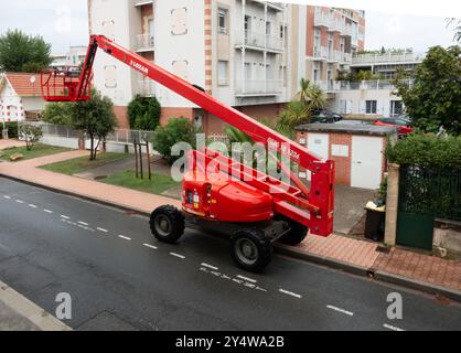 A bright red Haulotte Cherry Picker lift stands parked on a residential street. Stock Photo