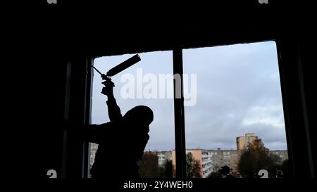 Construction worker is installing a window in a building using expanding foam insulation to seal it Stock Photo