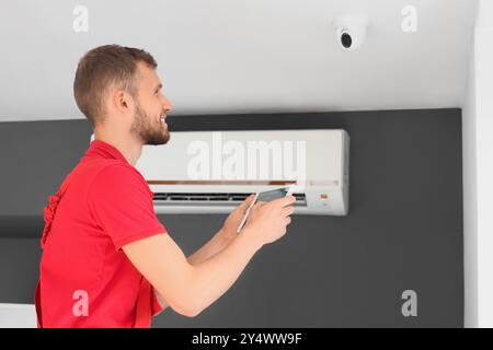 Male worker installing alarm system on ceiling in room Stock Photo