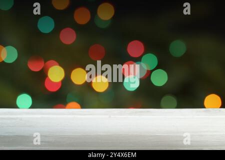 Empty white wooden table in front of blurred Christmas lights background Stock Photo