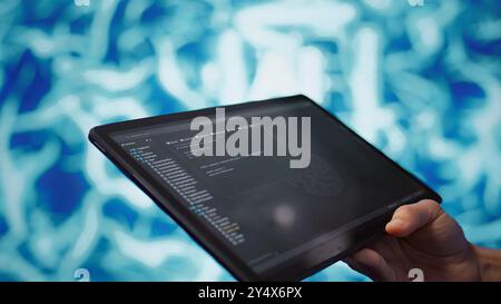 Software developer with tablet programming artificial intelligence computing simulating human brain. Close up of IT professional using device, building AI machine learning algorithms, camera B Stock Photo