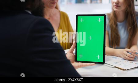 Financial adviser assisting clients in setting up investment accounts with green screen tablet, conducting audit. Consultant uses financial planning software on mockup device to help family, camera A Stock Photo