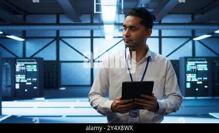 Security analyst in data center monitoring security threats, implementing cybersecurity measures. Expert ensuring compliance with regulations to protect data center assets, camera B Stock Photo