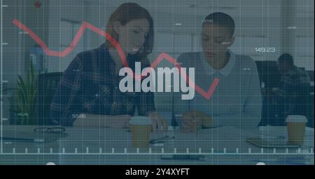 Declining stock market graph image over two businesswomen discussing documents in office Stock Photo