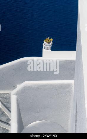 Traditional whitewashed house wall with cactus in white tiles and the  deep blue sea in the background .Santorini, Greece Stock Photo