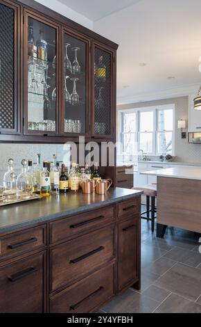 Dark wood bar in kitchen with bottles and glassware Stock Photo