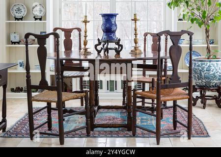 Antique table in sunroom with small dollhouse visible under table Stock Photo