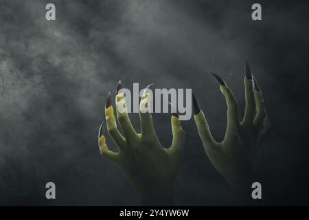 Two witches hand with with long nail claw. The color is green. Evil, zombie, or monster hand is shown in a dark room. The scene is eerie and unsettlin Stock Photo