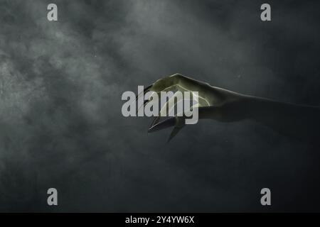 Witches hand with long nail claw. The color is green. Evil, zombie, or monster hand is shown in a dark room. The scene is eerie and unsettling. Hallow Stock Photo