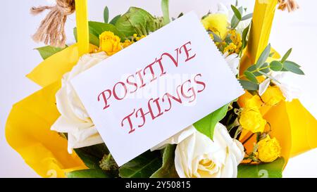 POSITIVE THINGS phrase on a white card on a background of flowers Stock Photo
